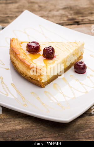 Stück Käsekuchen mit Kirsche auf weiße Schale. Restaurant Dessert Hintergrund Stockfoto