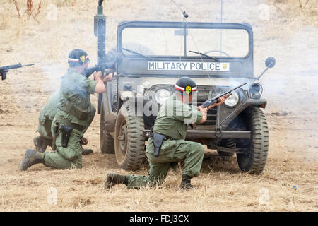 Vietnam Krieg Re-enactment. Scheingefecht. US-amerikanische Parlamentarier, der Militärpolizei, aus dem Hinterhalt auf der Straße, unter der Abdeckung hinter dem Jeep und wieder Feuer. Stockfoto