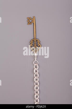 Vintage Schlüssel mit Kette auf grauem Hintergrund Stockfoto
