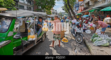 Anbieter helfen Kunden mit ihren Einkaufstaschen bei Pak Khlong Talat Blumenmarkt. Bangkok, Thailand. Stockfoto