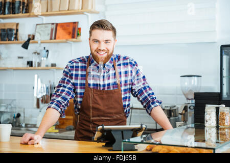 Potrait glücklich schöne Barista im karierten Hemd und braune Schürze stehen im Coffe-shop Stockfoto