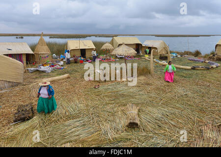 Titicacasee, Peru - 5. September 2015: Menschen vor Ort in traditionellen Gewändern willkommen Touristen kommen mit dem Boot auf den Inseln der Uros. Stockfoto