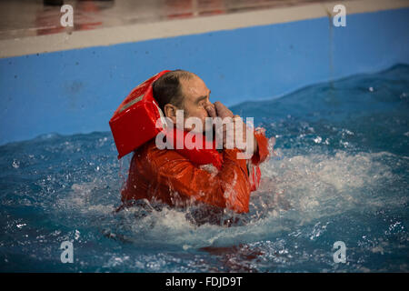 Ein Offshore-Arbeiter im Meer Überlebenstraining tragen einer Rettungsweste wieder auftaucht, während Meer Überlebenstraining. Stockfoto