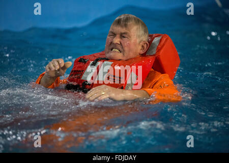 Ein Offshore-Arbeiter im Meer Überlebenstraining tragen einer Rettungsweste wieder auftaucht, während Meer Überlebenstraining. Stockfoto