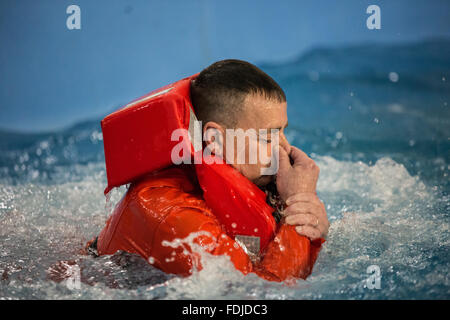 Ein Offshore-Arbeiter im Meer Überlebenstraining tragen einer Rettungsweste wieder auftaucht, während Meer Überlebenstraining. Stockfoto