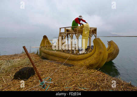 Titicacasee, Peru - 5. September 2015: Menschen vor Ort in traditionellen Gewändern willkommen Touristen kommen mit dem Boot auf den Inseln der Uros. Stockfoto