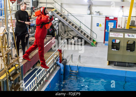 Ein Offshore-Arbeiter tragen einen Überlebensanzug springt 3 Meter in ein Becken im Meer Überlebenstraining. Stockfoto