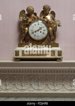 Der Kaminsims Uhr mit Putten flankieren das Ziffernblatt in Lady Iliffe Schlafzimmer in Basildon Park, Berkshire. Stockfoto