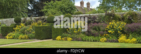 Spätsommer Pflanzen und Formschnitt Absicherung flankieren das Tor für die Einfahrt in den Garten erstellt von Simon Sainsbury und Stewart Grimshaw im Woolbeding House, West Sussex. Stockfoto