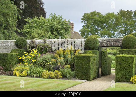 Spätsommer Pflanzen und Formschnitt Absicherung flankieren das Tor für die Einfahrt in den Garten erstellt von Simon Sainsbury und Stewart Grimshaw im Woolbeding House, West Sussex. Stockfoto