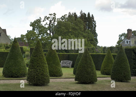 Blick Richtung der rustikalen Bank über die Hecke im Garten erstellt von Simon Sainsbury und Stewart Grimshaw im Woolbeding House, West Sussex. Stockfoto