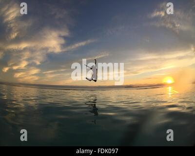 Silhouette einer Frau in Luft über Meer springen Stockfoto