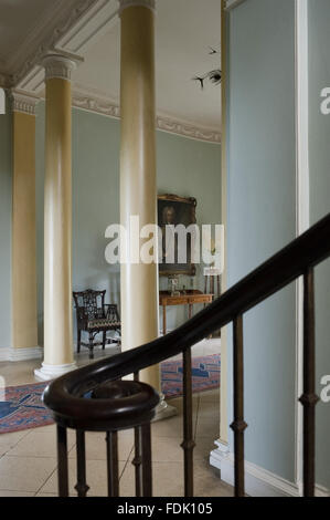 Detail der Schmiedeeisen Geländer der Treppe und zwei dorischen Säulen hinaus der Eingangshalle im Newark Park, Gloucestershire. Stockfoto