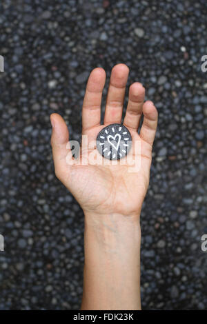 Hand hält ein Herz gemalt auf einen kleinen Stein Stockfoto