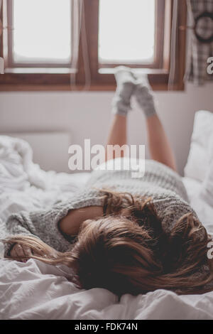 Frau, Gesicht nach unten auf einem Bett liegend Stockfoto