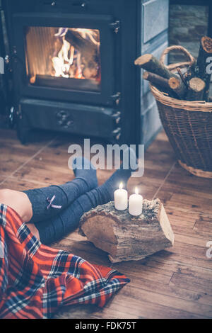 Frau sitzt vor einem Kamin Stockfoto