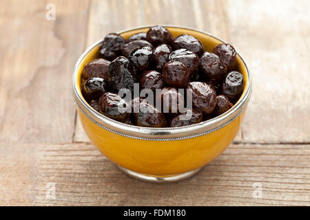 Gelbe Schale mit schwarzen Oliven auf den Tisch Stockfoto