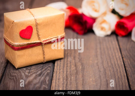 Geschenkbox mit Bewegungsunschärfe roten und weißen Rosen auf einem dunklen Hintergrund aus Holz. Frauen ' s Tag, Valentinstag, Muttertag. Textfreiraum, sel Stockfoto