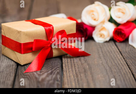 Geschenkbox mit Bewegungsunschärfe roten und weißen Rosen auf einem dunklen Hintergrund aus Holz. Frauen ' s Tag, Valentinstag, Muttertag. Textfreiraum, sel Stockfoto