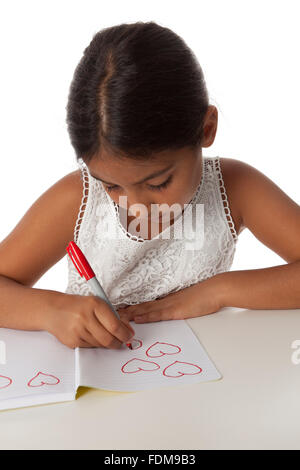 Junge Teenager-Mädchen zeichnen kleine Herzen in ihr Notizbuch auf weißem Hintergrund Stockfoto