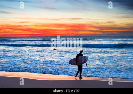 Surfer mit Surfbrett zu Fuß am Strand in der majestätischen Sonnenuntergang Stockfoto