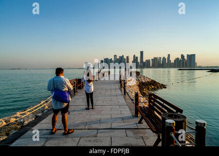 Touristen fotografieren mit den Wolkenkratzern von West Bay im Hintergrund, Doha, Katar Stockfoto