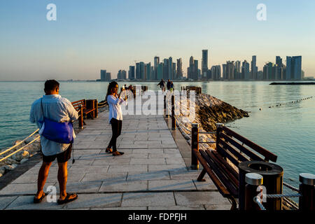 Touristen fotografieren mit den Wolkenkratzern von West Bay im Hintergrund, Doha, Katar Stockfoto