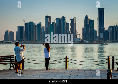 Touristen fotografieren mit den Wolkenkratzern von West Bay im Hintergrund, Doha, Katar Stockfoto