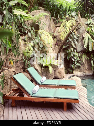Zwei Liegestühle am Pool willkommen im The Farm at San Benito, Philippinen eine Wasserfall-Pool entspannen. Stockfoto