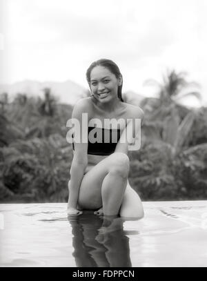 Eine Frau sitzt auf der Kante der Infinitypool The Farm at San Benito, Philippinen. Stockfoto