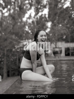 Eine Frau sitzt auf der Kante der Infinitypool The Farm at San Benito, Philippinen. Stockfoto