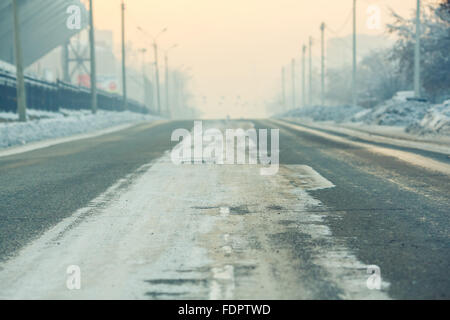 Hintergrund auf einer leeren Straße in der Stadt, kalten Wintertag mit Schnee und Reagenzien bei Dämmerung, Antenne Perspektive. Lichtmasten an Rändern der Straße. Stockfoto