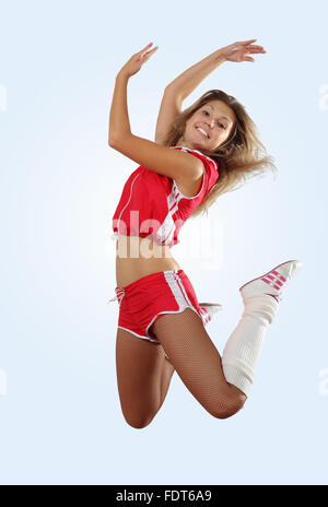 Uniformierte Cheerleader springt hoch in die Luft isoliert auf weiss. Stockfoto