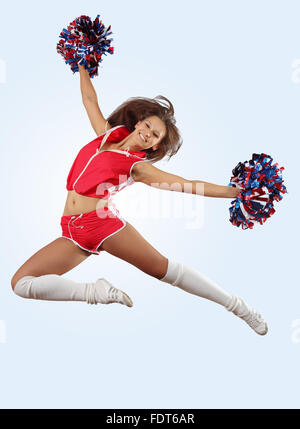 Uniformierte Cheerleader springt hoch in die Luft isoliert auf weiss. Stockfoto