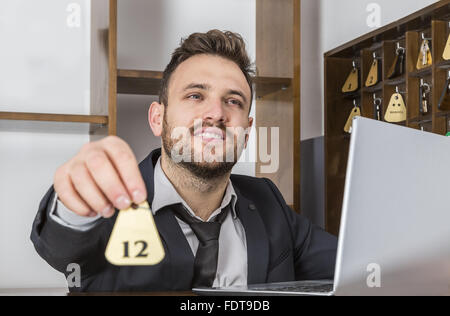 Bild der Empfangsdame an seinem Schreibtisch, geben den Schlüssel an einem Client. Selektiven Fokus auf dem Gesicht. Stockfoto