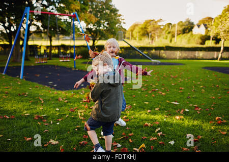 Zwei glückliche Jungen spielen zusammen im Park, Blätter werfen. Stockfoto