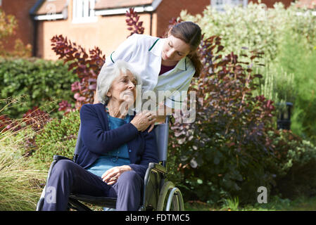 Pflegeperson Senior Frau im Rollstuhl schieben Stockfoto