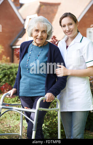 Pflegeperson helfen Senior Woman, Spaziergang im Garten mit Walking Frame Stockfoto