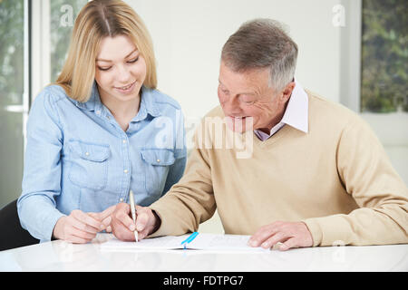 Senior Woman spielen Sudoku Anzahl Puzzle mit Tochter im Teenageralter abschließen Stockfoto