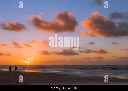 Menschen, die einen Sonnenuntergang genießen Fuß am Strand von Katwijk Aan Zee, Südholland, Niederlande. Stockfoto