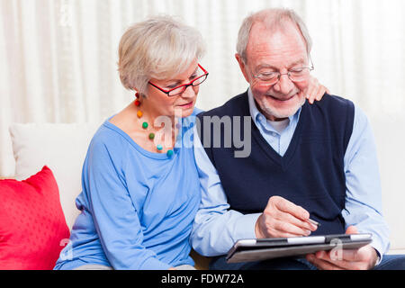 gerne älteres paar zu Hause Surfen Internet auf Tablett Stockfoto