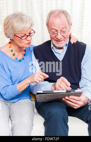 gerne älteres paar zu Hause Surfen Internet auf Tablett Stockfoto