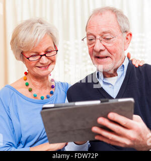 gerne älteres paar zu Hause Surfen Internet auf Tablett Stockfoto