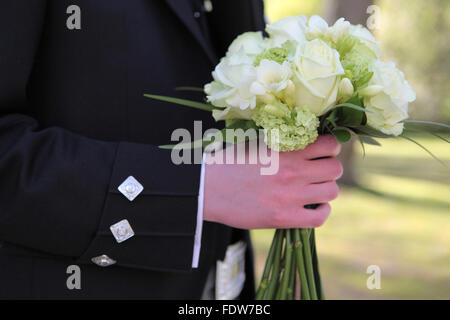 Bräutigam in traditionelle schottische Hochzeit Outfit hält die Bräute bouquet Stockfoto