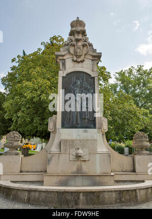 Religiöses Denkmal mit Brunnen in der Nähe von St. Michael Basilica (ehemals Stiftskirche) am Mondsee, Österreich. Stockfoto