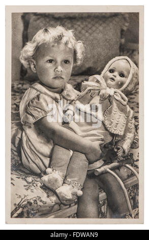 Kleines Mädchen mit einer großen Puppe spielt. Vintage Bild mit originalen Filmkorn und Unschärfe Stockfoto