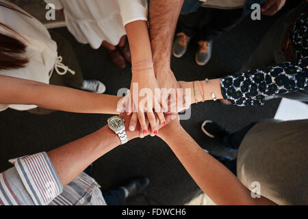 Draufsicht von jungen kreativen Profis, die ihre Hände als Symbol der Teamarbeit, Zusammenarbeit und Einheit zusammenfügen. Stapel von h Stockfoto