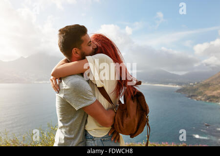 Portrait über ein glückliches junges Paar eine romantische Umarmung im Freien zu genießen. Junger Mann umarmt seine Freundin beim stehen auf einem Hügel Stockfoto