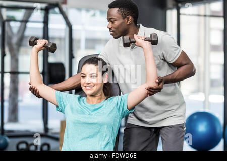 Sportliche Frau Heben von Gewichten von Trainer geholfen Stockfoto