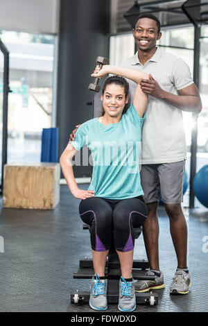 Sportliche Frau Heben von Gewichten von Trainer geholfen Stockfoto